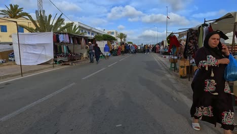People-walk-on-the-street-of-the-open-air-market-of-Midoun-in-Djerba,-Tunisia