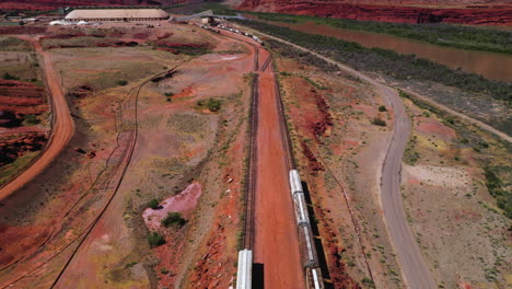Drone-shot-over-trains-resting-at-a-red-sand-railway-station,-in-sunny-South-USA