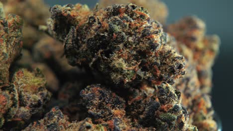 A-macro-cinematic-detailed-shot-of-a-cannabis-plant,-orange-hybrid-strains,-Indica-and-sativa-,-dark-purple-green-marijuana-flower,-on-a-rotating-stand,-slow-motion,-4K,-professional-studio-lighting