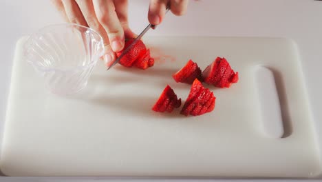 Hand-braces-whole-strawberry-against-cutting-board-to-thinly-slice-pieces