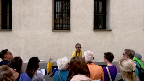 View-Behind-Tour-Group-Listening-To-Energetic-Italian-Tour-Guide-Speaking-Enthusiastically-In-Milan,-Italy