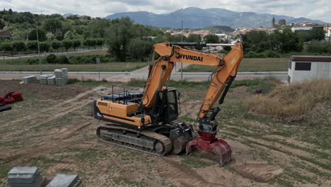 An-orange-Hyundai-bulldozer-sits-dormant-awaiting-next-shift,-aerial