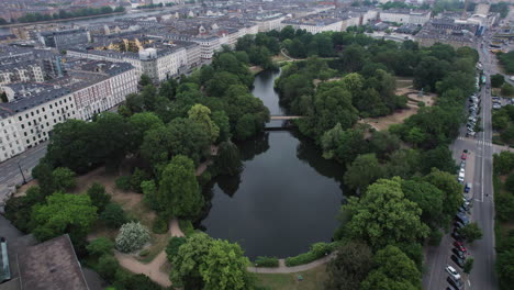 From-the-air,-Ørstedsparken-stands-out-with-its-lush-foliage-and-scenic-lakes,-embraced-by-the-city's-central-buildings-in-Copenhagen