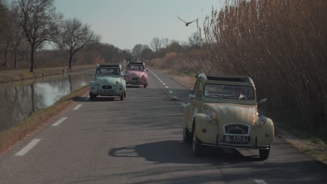 Three-retro-Citroens-CV-2-with-canvas-roofs-overtake-each-other-on-the-road
