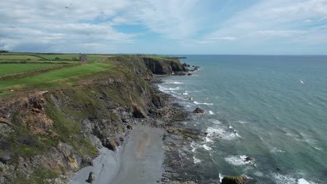 Drone-seascape-at-The-Copper-Coast-Waterford-Ireland-circling-seagulls-fly-over-the-sea-cliffs-on-a-summer-day