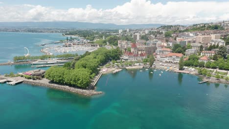 Drone-flying-over-Lake-Geneva-towards-Chateau-d'Ouchy-in-Lausanne,-Switzerland