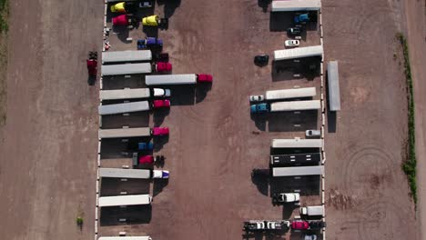 top-down-aerial-of-yard-parking-lot-with-semi-trucks-and-trailers---reefers,-dry-van,-flatbeds,-stingers,-bob-tails