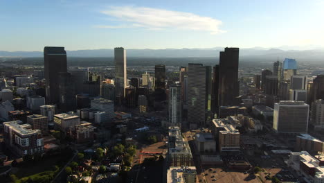 Aerial-cinematic-drone-mid-summer-early-fall-Downtown-Denver-Colorado-mile-hight-city-buildings-traffic-wisp-clouds-blue-sky-afternoon-sunset-stunning-golden-hour-light-circling-pan-to-the-left-motion
