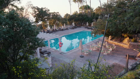 Ein-Verlassener-Poolbereich,-Umgeben-Von-Bäumen-Am-Meer,-Der-Die-Ruhige-Ruhe-Des-Sommers-Ohne-Touristen-Einfängt