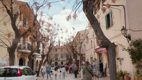 A-bustling-shopping-street-filled-with-passersby-on-a-sunny-day-in-Valldemossa,-Mallorca,-Spain