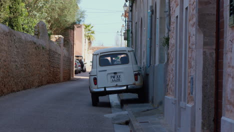 An-old-car-parked-on-a-street-in-Palma-de-Mallorca,-surrounded-by-red-stone-houses,-painting-a-typical-local-scene