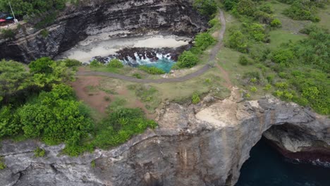 Luftaufnahme-Des-Kaputten-Strandes-Auf-Der-Insel-Nusa-Penida-Und-Ihrer-Natürlichen-Bogenbrücke,-Bali