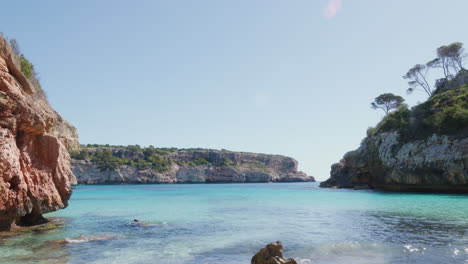 A-stunning-bay-in-Mallorca,-featuring-turquoise-waters-embraced-by-unique-rock-formations,-presenting-a-picture-perfect-scene-of-natural-beauty