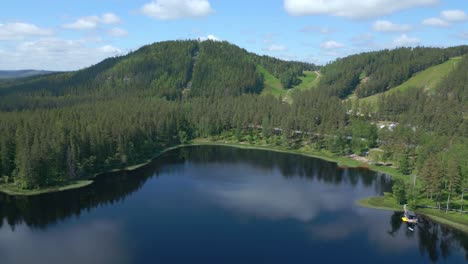 Beautiful-drone-shot-Isaberg-mountain-resort-and-lake-in-summer-sun