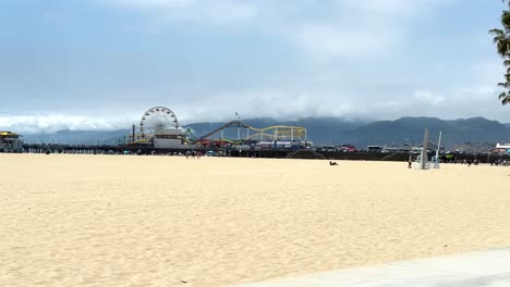 Santa-Monica-Pier-Amusement-Park,-Beach-and-People-Walking-and-Jogging-on-Hot-Sunny-Day,-Riding-POV