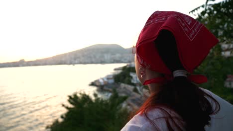 Girl-with-a-scarf-watching-the-sunset-over-the-city-of-Saranda