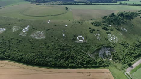 Fovant-set-of-regimental-badges-carved-into-chalk-hillside-aerial-view-panning-across-the-Wiltshire-countryside