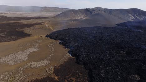 Tourist-standing-near-black-basalt-rock-lava-field-in-Iceland,-aerial