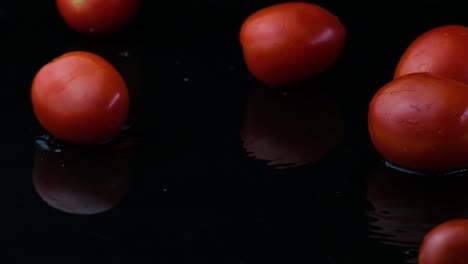 Kirschtomaten-Sitzen-Im-Seichten-Wasser-Und-Spiegeln-Die-Rote-Saftigkeit-Im-Wasser-Mit-Schwarzem-Hintergrund-Wider