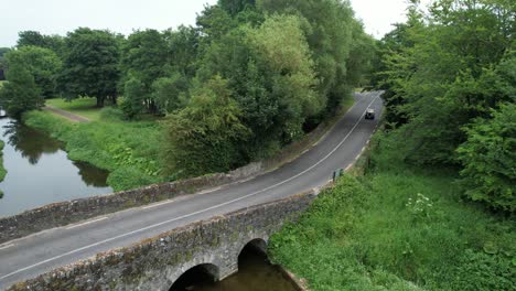 Gelber-Oldtimer,-Der-An-Einem-Warmen-Junitag-Auf-Einer-Oldtimer-Rallye-In-Irland-über-Die-Malerische-Alte-Brücke-Fährt