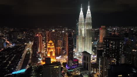 Toma-Aérea-Nocturna-De-Drones-De-La-Ciudad-De-Kuala-Lumpur-Con-Las-Torres-Petronas-Iluminadas