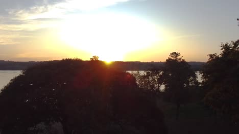 Cinematic-aerial-footage-of-the-sunset-behind-trees-in-Misiones,-Jardin,-America,-Argentina,-Drone