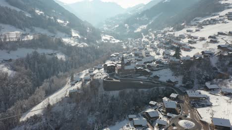 Aerial-of-a-beautiful-mountain-town-with-a-church-in-the-center-in-winter