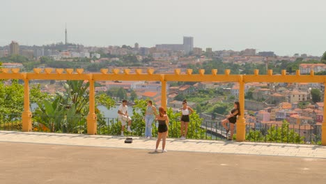 Pan-shot-of-tourists-enjoying-scenic-viewpoint-from-Porto-side-of-Vila-Nova-de-Gaia-across-Douro-river-in-Porto,-Portugal-on-a-cloudy-day