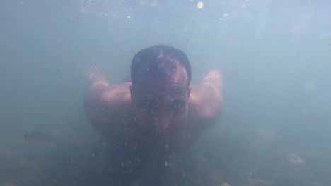 Mann-Schwimmt-Im-Schmutzigen-Wasser-Des-Flusses,-Unterwasseransicht-Mit-Sonnenlichtstrahlen-Am-Morgen