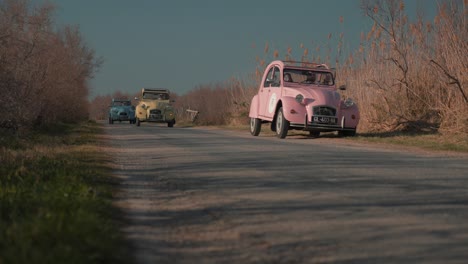 Three-retro-cars-of-different-colors-are-driving-in-a-row-along-the-road
