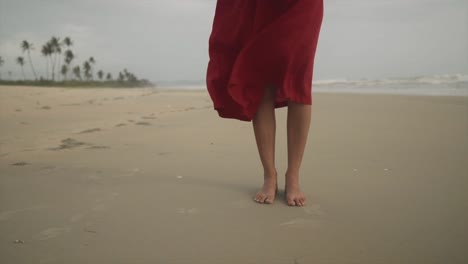Close-shot-of-female-legs-while-standing-barefoot-at-the-sandy-beach