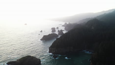 Luftaufnahme-Rückwärts-über-Der-Nebligen-Küste-Von-Oregon,-Dunstiger-Sonnenaufgang-In-Den-USA