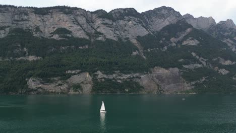 White-yacht-sails-leisurely-in-Walensee-lake-creating-peaceful-scene