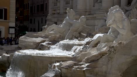 Un-Primer-Plano-En-Cámara-Lenta-Del-Agua-En-Cascada-De-La-Fuente-De-Trevi-Y-Las-Esculturas-Circundantes-En-Un-Día-Soleado,-Roma,-Italia