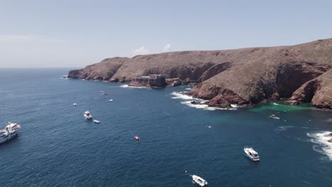 Sightseeing-tourist-boats-on-Sao-Joao-Baptista-das-Berlengas-coast-aerial-view-approaching-the-Portuguese-island-cove