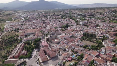 Establishing-aerial-view-rising-back-over-San-Marti-n-de-Valdeiglesias-idyllic-traditional-Spanish-town-streets-and-mountain-landscape