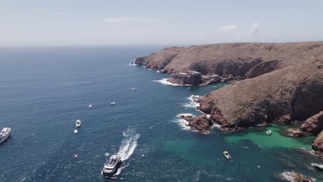 Aerial-view-orbiting-tourist-boats-on-Sao-Joao-Baptista-das-Berlengas-Portuguese-Berlenga-Grande-island-coast