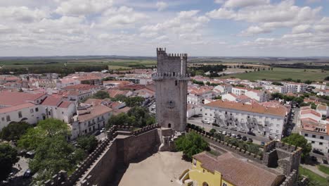 Establishing-aerial-view-over-Baixo-Alantejo-whitewashed-red-tiled-building-rooftops-to-reveal-castle-Beja-Portuguese-fortress