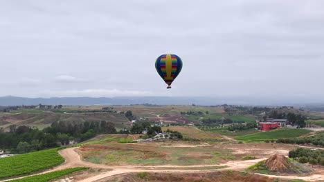 Hot-air-balloon-aerial-pull-back-over-Temecula-Countryside-Vineyard-in-wine-country-on-an-over-cast-day