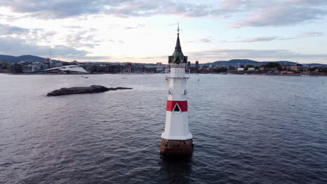 Aerial-circling-Kavringen-Lighthouse-in-partially-cloudy-day,-Oslo,-Norway