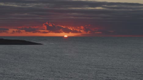 Sunset-with-rich-orange-sky-over-coast-of-Devon,-UK-in-a-wide-shot