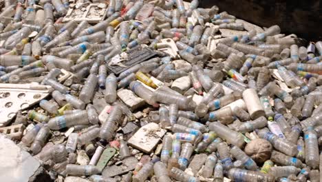 Nahaufnahme-Eines-Verschmutzten-Baches-Voller-Plastikwasserflaschen-Und-Müll,-Der-Durch-Ein-Tor-In-Der-Hauptstadt-Dili,-Timor-Leste,-Südostasien-Daran-Gehindert-Wird,-Den-Ozean-Zu-Verschmutzen