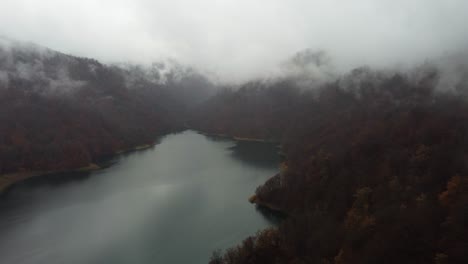 Aerial-flight-over-mountain-lake-in-heavy-grey-overcast-cloud-and-rain