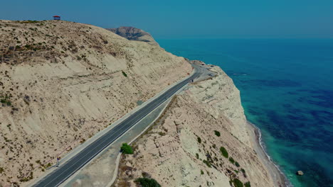 Experience-the-captivating-charm-of-the-Mediterranean-from-the-Aphrodite's-Rock-Viewpoint,-a-drone-flight-over-its-scenic-highway,-showcasing-the-magnificent-sea-of-Cyprus
