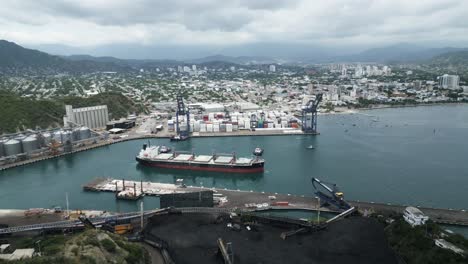 Aerial-View-of-Santa-Marta,-Colombia,-Cargo-Ship-in-Harbor-and-Waterfront-Buildings