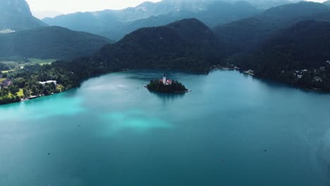 Filmischer-Drohnenflug-über-Den-Blauen-See-Mit-Der-Berühmten-Kirche-Mariä-Himmelfahrt-In-Bled,-Slowenien