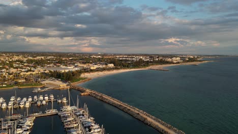 Aerial-view-of-Fremantle-Harbor-and-boats-with-South-Beach-in-the-distance-at-sunset,-Australia