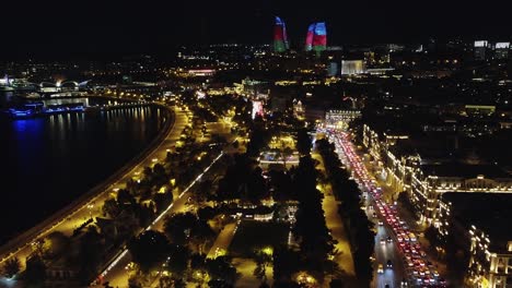 Busy-city-streets,-Flame-Towers-in-night-aerial-over-Baku-Azerbaijan