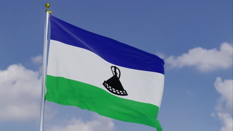 Bandera-De-Lesotho-Moviéndose-En-El-Viento-Con-Un-Cielo-Azul-Claro-En-El-Fondo,-Nubes-Moviéndose-Lentamente,-Asta-De-Bandera,-Cámara-Lenta