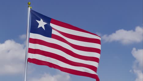 Bandera-De-Liberia-Moviéndose-En-El-Viento-Con-Un-Cielo-Azul-Claro-En-El-Fondo,-Nubes-Moviéndose-Lentamente,-Asta-De-Bandera,-Cámara-Lenta